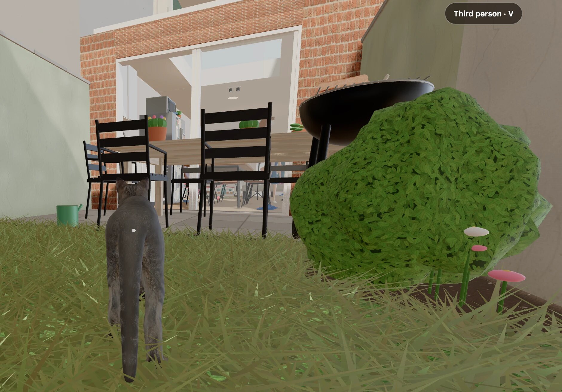 The cat walking through the long grass of the back garden towards the open patio doors of the brick house, past a barbecue, a bush with flowers and a green watering can. A badge reads 'Third person · V'.